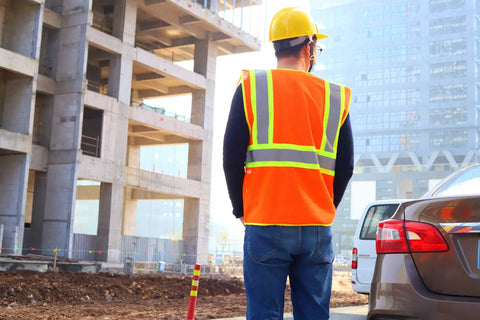 Construction worker wears High Visibility Reflective Safety Vest With Zipper And Pockets In Orange Size M For Men And Women at work site.