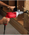 Heavy Duty Corded Power Drill With Beast Mode 8 Amp Motor Delivering Up To 850 Rpm And Variable Speed Trigger Plus Rotating Side Handle And Keyed Chuck drilling into wood.