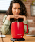 Grab This Solid Self Heating Coffee Mug To Keep Your Morning Sips Piping Hot With Smart Temperature Controls And A Ridiculously Long Battery Built From Premium Stainless Steel For Office Or Travel Cherry Red on a table.