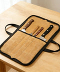 Open canvas knife roll on a table showing four slots with knives, featuring water-repellent material for chefs and outdoor use.