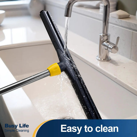 Big Time Heavy Duty Floor Squeegee Scrubber With Adjustable Telescopic Pole and Ergonomic Grip, rinsing under faucet.
