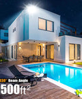 Outdoor 150W LED Flood Light With Dusk To Dawn Photocell illuminating a modern house pool area at night, wide beam.