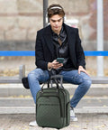 Man seated on a bench with Underseat Carry-On Roller Luggage 16 Inch Lightweight Bag With Wheels For Men And Women, Army Green