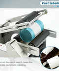 Plug And Play Semi Automatic Round Bottle Labeler With Tight Grip Adjustment Handles 15 To 150Mm Bottles, close-up of label application.