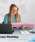Person holding pink binder, laptop on desk. Label: Two Inch Three Ring Binder With Clear View Cover And Two Inside Pockets