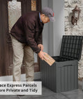Man places parcel in 31 Gallon Weatherproof Resin Deck Box With Lid For Indoor Outdoor Storage Durable Grey Outdoor Storage Container.