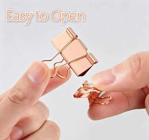 Close-up of hands holding two Rose Gold Binder Clips Set In Assorted Sizes Mini Small Medium Large 100 Pcs In Clear Box for easy opening.