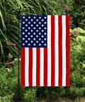 All American Fourth Of July Garden Flag Outdoor Decor Made In The USA Premium Poly Poplin Weather Resistant Double Sided Fade Resistant Patriotic Stars And Stripes Flag For Patio Lawn Yard displayed amidst garden greenery.