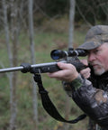 Person aiming with rifle featuring Vibration Dampening Barrel Device For Standard Barrels NAVCOM Material Cuts Barrel Whip.