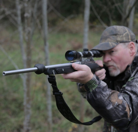 Person aiming with rifle featuring Vibration Dampening Barrel Device For Standard Barrels NAVCOM Material Cuts Barrel Whip.