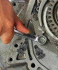 Hand using wrench on Durable Iron Transmission Gear Reduction Unit Packing Serious Gasoline Engine Kick And Tough As Nails Torque.