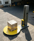 Heavy Duty Automatic Pallet Wrapping Machine With Wide Stretch Film Roll Wrapper operating with a pallet of boxes on a yellow turntable.
