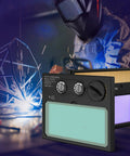 HD Auto Darkening Welding Lens With True Color View, Solar Powered, Two Arc Sensors, Helmet Lens with welder in background.