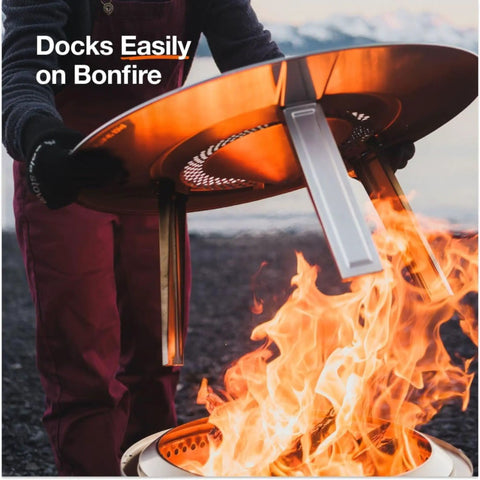 Person placing Bonfire Heat Deflector For Fire Pits, Boost Warmth And Comfort With A Wide Heat Radius over fire