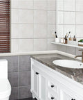 Bathroom with tiled walls, marble sink, brown blinds, and white storage cabinets under countertop with accessories