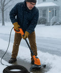 Man using heavy duty 200 ft outdoor extension cord with 14 gauge 3-conductor SJTW, lighted end and triple outlet in snowy weather.