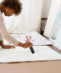 Woman using Premium Top Shelf Paint Roller And Bristle Brush Kit With Heavy Duty No Drip Tray for painting on white paper.