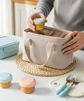 Person placing a colorful sauce cup into a lunch bag from the Eight Pack 2 Oz Salad Dressing Containers To Go With Lids For Lunch Boxes And Bento