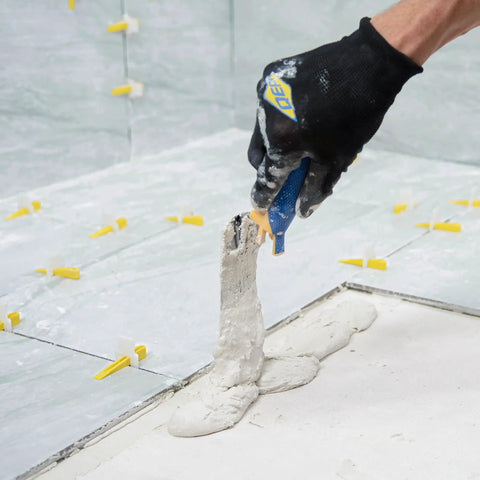 Comfort Grip 6 In By 2 In Flat Margin Flooring Trowel With Bucket Hook applying thinset to a floor in tight space