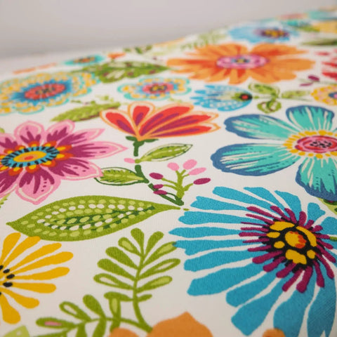 Close-up of bright floral indoor outdoor tufted wicker chair pad fabric with ties, featuring blue purple Gregoire pattern.