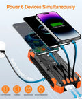 Solar Charger Power Bank With Built In Cables And 42800mAh Battery charging six devices, showing USB cables and wireless function.