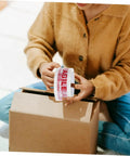 Person holding Fragile Warning Packing Tape Set with 5 rolls, preparing to seal a box for shipping
