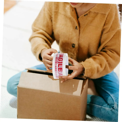 Person holding Fragile Warning Packing Tape Set with 5 rolls, preparing to seal a box for shipping