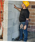 Man wearing cut resistant wrist sleeves with breathable forearm guards while inspecting a wall during construction work.