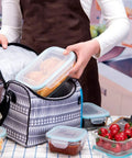 Person placing large rectangle container from 18 Piece Glass Food Storage Set With Lids BPA Free And Leak Proof in a lunch bag.