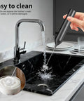 Rechargeable Handheld Milk Frother With Stand For Coffee Lattes Cappuccinos Matcha And More Quiet Fast Foam Wand In 15 To 30 Seconds USB Rechargeable Kitchen Gift Black being washed under tap water in a kitchen sink.