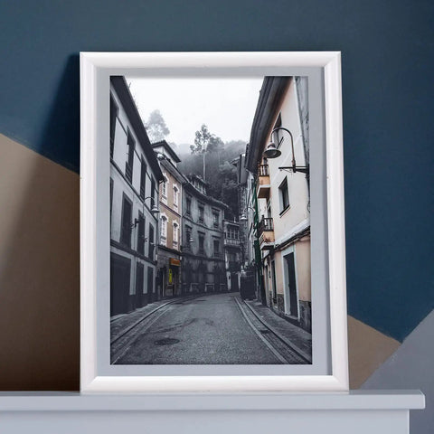 Framed black and white photo of a European street on a dark blue and beige background wall.