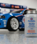 Front view of Permatex Anti-Seize Lubricant bottle with brush top, 8 oz, gray bottle with blue logo; blue car in workshop