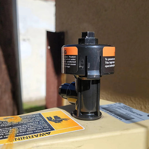 Front view of black plastic high-flow manual relief valve with orange warning labels mounted on a pool spa filter canister.