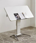 No Sweat Adjustable Height Rolling Drafting Desk With Flip Top And Book Stop Lightweight White Mobile Workstation Craft Table For Home Office Easy Roll Setup Stepless Tilt Surface Built Solid showing tilted white surface with magazine.