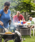 Person grilling on Premium 22 Inch Charcoal Grill Portable Outdoor BBQ Grill With Durable Plated Steel Grates Porcelain Enamel Bowl And Precision Airflow Control For Bold Flavor On The Go Tailgate Ready