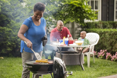 Person grilling on Premium 22 Inch Charcoal Grill Portable Outdoor BBQ Grill With Durable Plated Steel Grates Porcelain Enamel Bowl And Precision Airflow Control For Bold Flavor On The Go Tailgate Ready