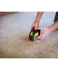 Person using Cross Line Laser Level With Green Beam Pro Grade Durable Overmolded Housing 1 Meter Drop Rating Magnetic Bracket Full Time Pulse Mode Ideal For Picture Hanging And DIY Renovations on floor.