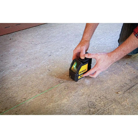 Person using Cross Line Laser Level With Green Beam Pro Grade Durable Overmolded Housing 1 Meter Drop Rating Magnetic Bracket Full Time Pulse Mode Ideal For Picture Hanging And DIY Renovations on floor.
