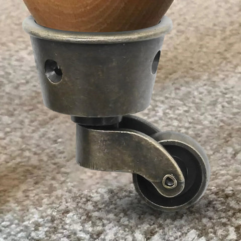 Close-up of Two Pack Vintage Zinc Alloy Swivel Caster Wheels with Antique Green Bronze Finish attached to furniture leg