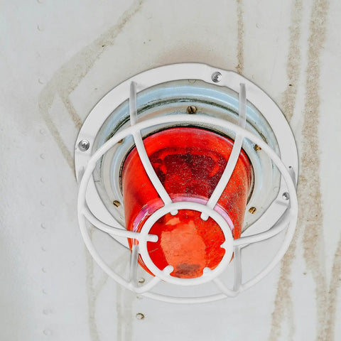Built Damn Tough Fire Sprinkler Head Protector Wire Cage Guard for ceiling mount with red light and white wire cage.