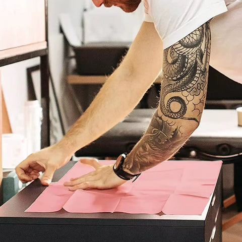Person arranging pink fake skin from Beginner Friendly All In One Tattoo Practice Kit With Pink Fake Skin, Ink Cups, Machine Covers