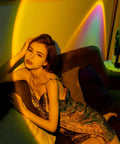 Person lounging under a Sunset Lamp Projector For Room With Remote Control, 16 Color RGB LED Night Light for cozy living room decor