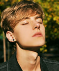 Real Good Titanium Flat Back Screw Back Stud Earrings In Crisp White 6Mm Post worn by young man with closed eyes outdoors.