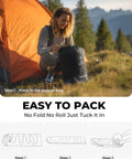 Woman packing Lightweight 3lb Backpacking Sleeping Bag For Adults And Kids With Compression Sack at a campsite next to a tent.