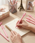 Writing with Pink Bow Pens Set 10 Pack Aesthetic Retractable Ballpoint Pens With Cute Bow Decor on a notebook