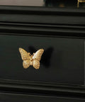 2 Pack Butterfly Cabinet Knobs In Gold Pewter With Delicate Wings and Lifelike Antennae Bringing Whimsical Vibes To Girls Room Dresser Vanity Hardware on black drawer.