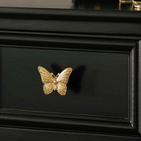 2 Pack Butterfly Cabinet Knobs In Gold Pewter With Delicate Wings and Lifelike Antennae Bringing Whimsical Vibes To Girls Room Dresser Vanity Hardware on black drawer.