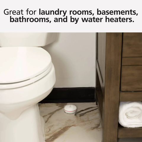 WiFi Water Leak Detector and Freeze Alarm with Alexa Compatibility placed on bathroom floor beside toilet and cabinet.
