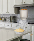 No Sweat Heavy Duty Cast Iron Grain Mill Featuring Wooden Hand Crank And Secure Table Clamp For Grinding Corn Wheat Oats Into Home Pantry Fresh Flour on kitchen countertop.