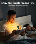 Man reading in bed using Amber Glow Clip On Book Light With 1800K Eye Care LED Rechargeable USB Reading Lamp, wife sleeping beside.